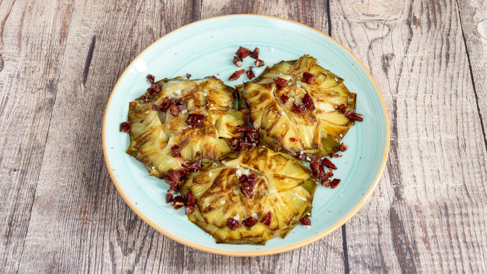 Doradas y crujientes, las alcachofas a la plancha con jamón son una forma sencilla de disfrutar este producto de temporada.