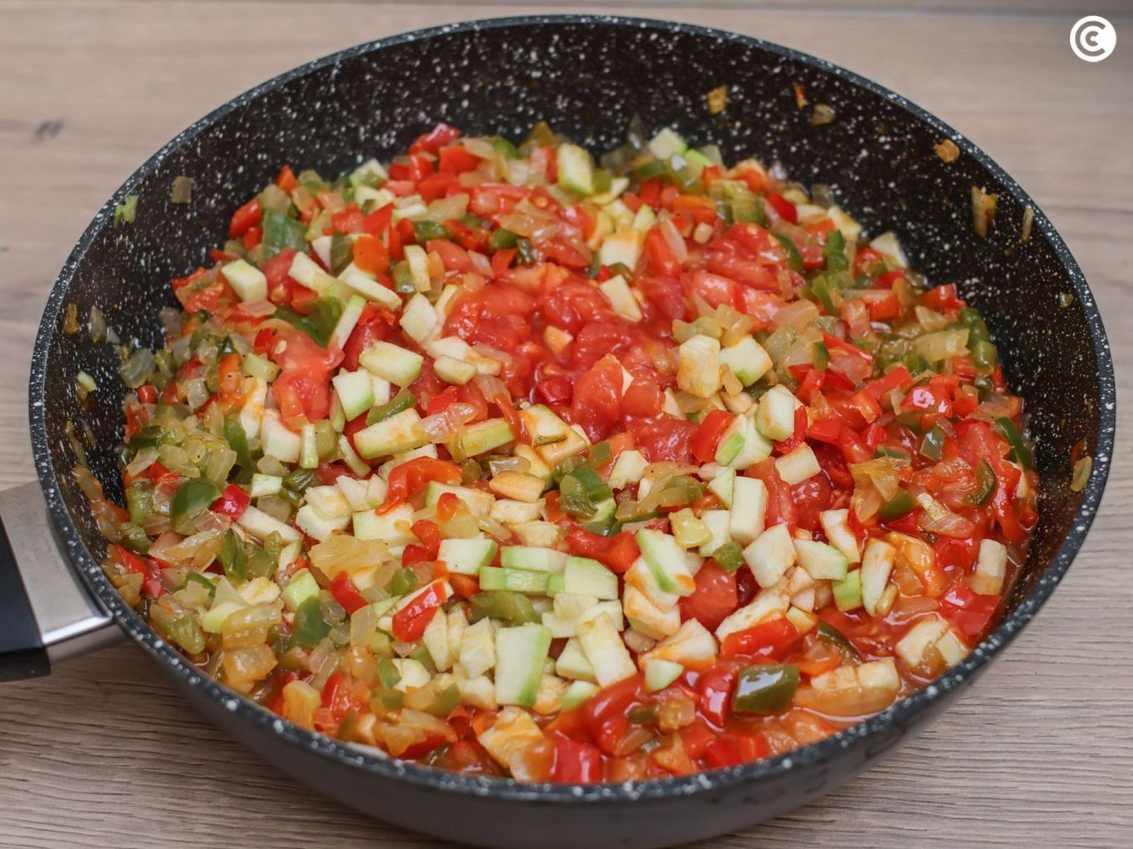 Agregar el tomate a las verduras para hacer el pisto