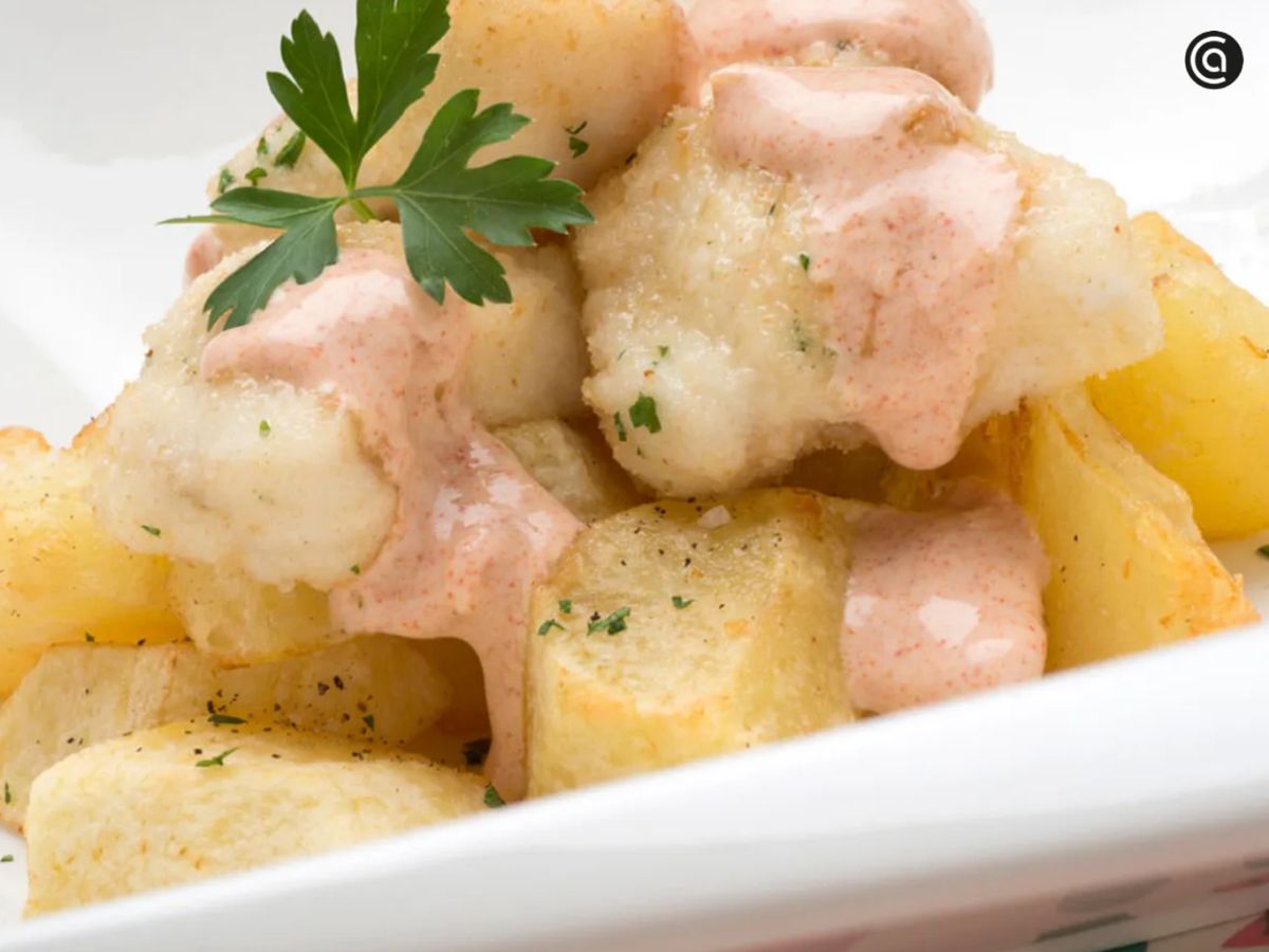 Rape empanado con patatas y salsa, un bocado suave realzado por una cobertura dorada y ligera.