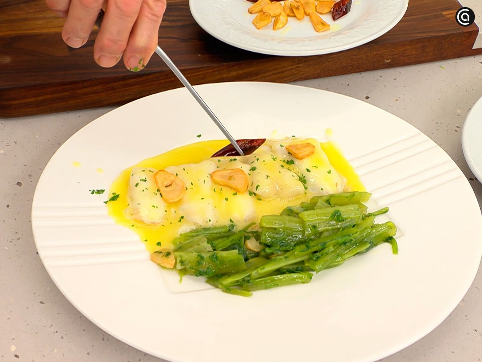 Coloca el ajo y las guindillas encima de las kokotxas de bacalao al pilpil