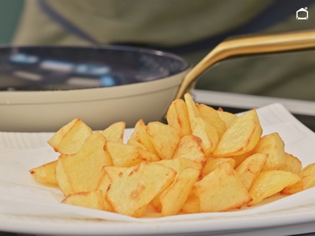 Las patatas ya fritas se ponen sobre papel absorbente antes del emplatado con la salsa brava.