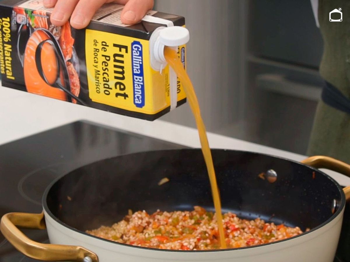 Agrega el fumet para hacer el arroz caldoso con gambas