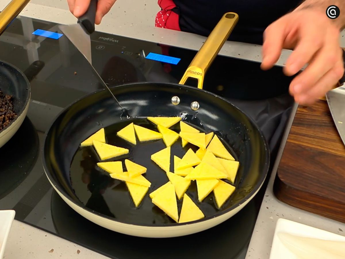 Trocea la polenta en triángulos, saltéalos y mézclalos con la morcilla y la cebolla