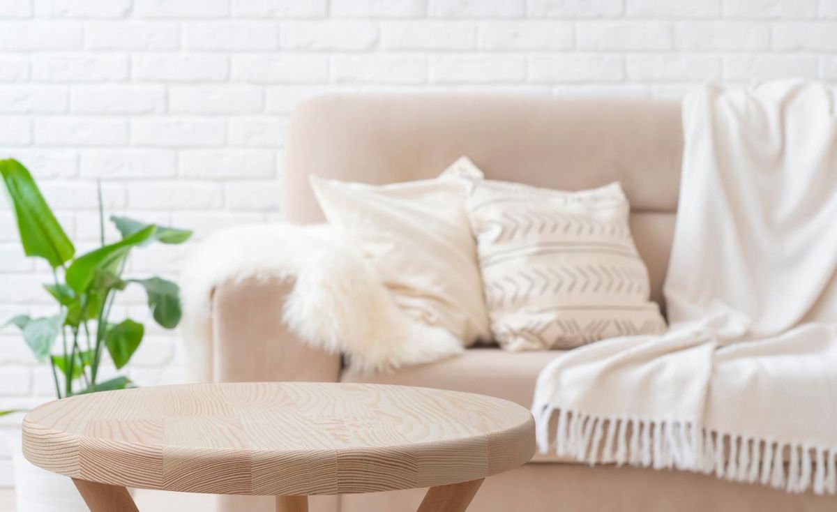 Sofá beige decorado con textiles en tonos claros.