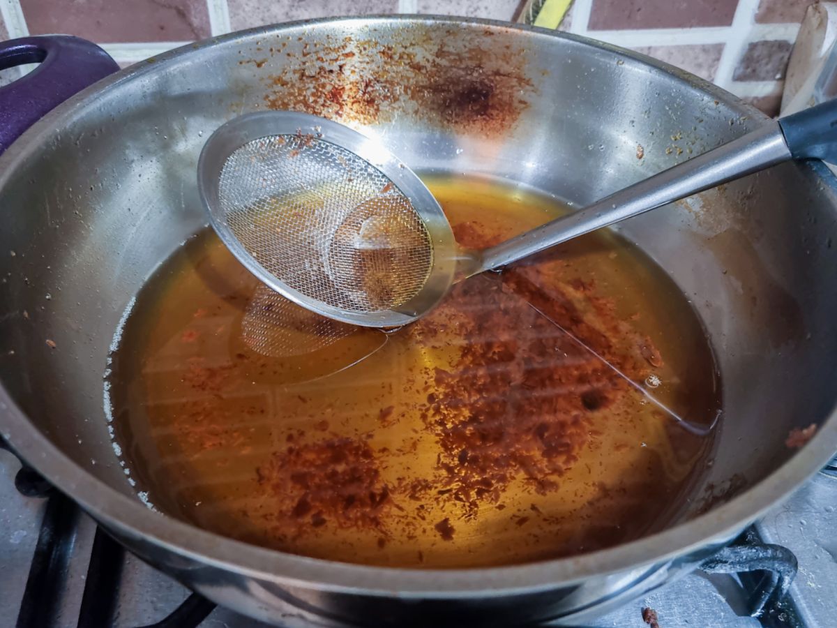 Aceite usado con restos sólidos tras freír, listo para ser clarificado.