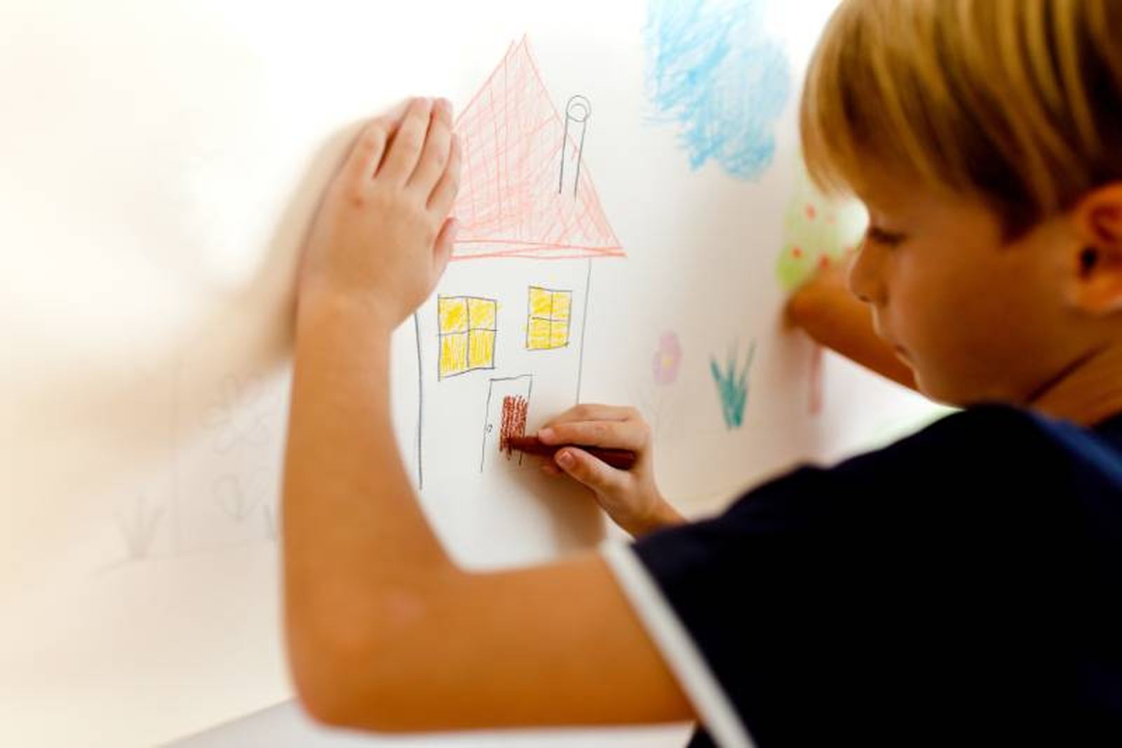 Un niño pintando una casita. Un niño pintando una casita.