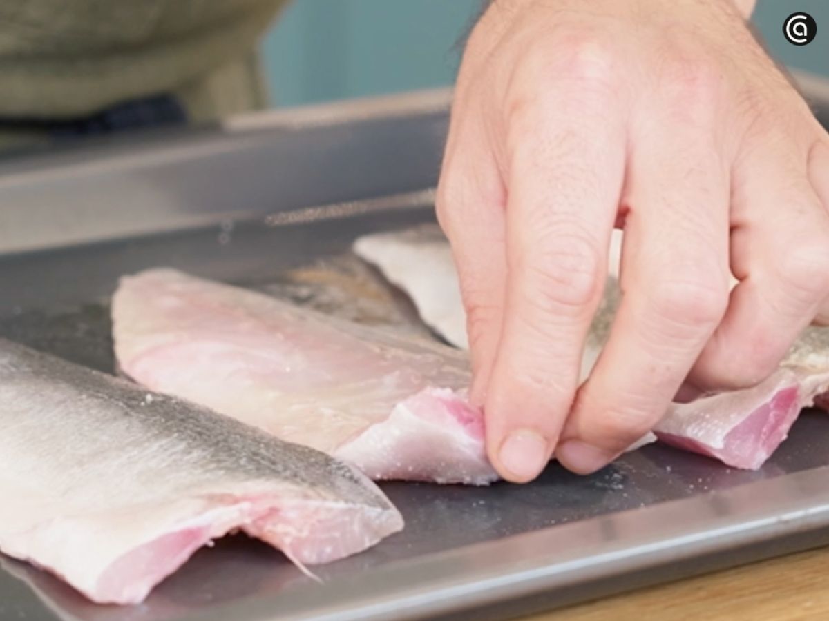 Unta los lomos de lubina con aceite de oliva y añade una pizca de sal antes de hornearlos.