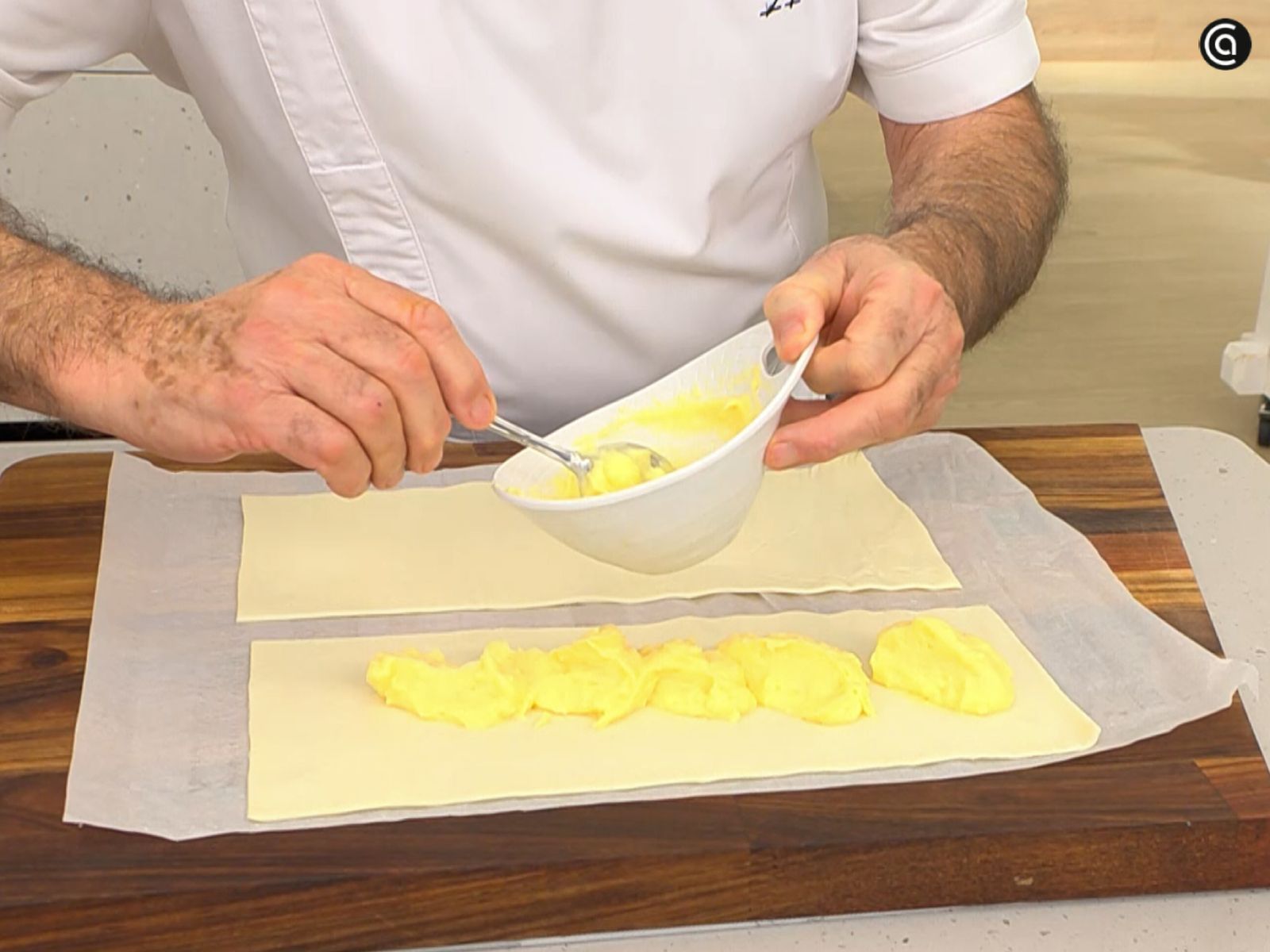 Reparte la crema pastelera sobre una de las mitades del hojaldre antes de montar los pastelitos.
