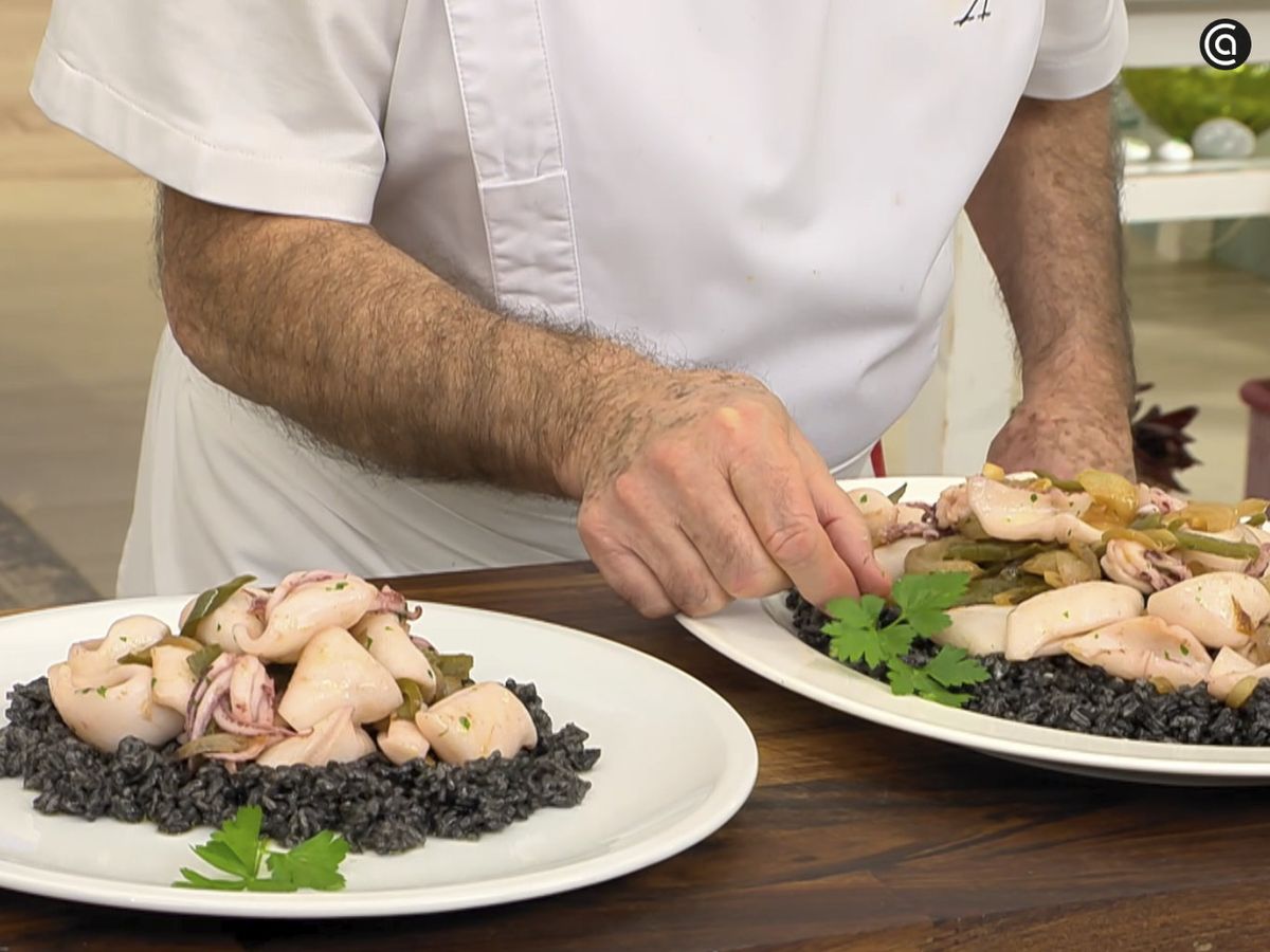 Pon una base de arroz negro y acompaña con el salteado de calamares encebollados