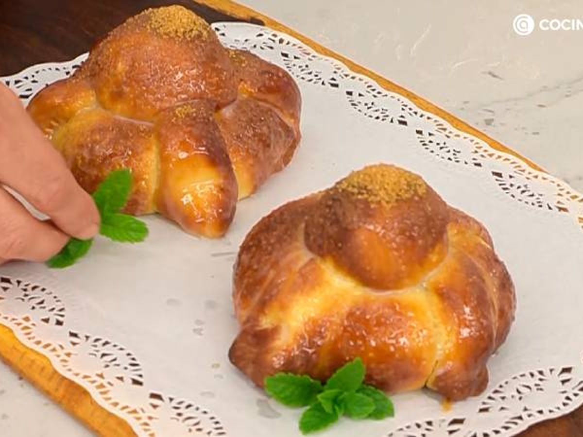 Unta el pan de muerto con una mezcla de leche y azúcar, y decora con azúcar moreno