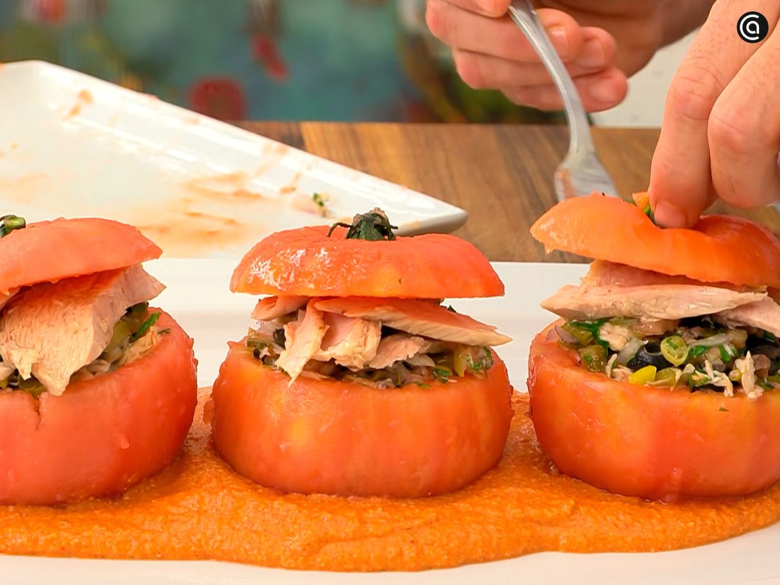 Coloca los tomates rellenos de ventresca sobre una base de muhammara Coloca los tomates rellenos de ventresca sobre una base de muhammara
