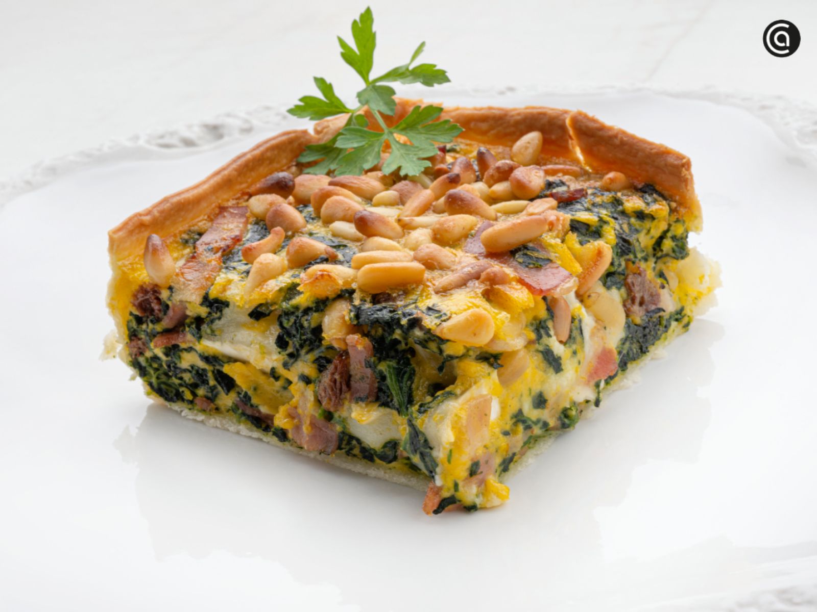 Una tarta salada irresistible, con pasas y piñones para dar el toque final. Una tarta salada irresistible, con pasas y piñones para dar el toque final.