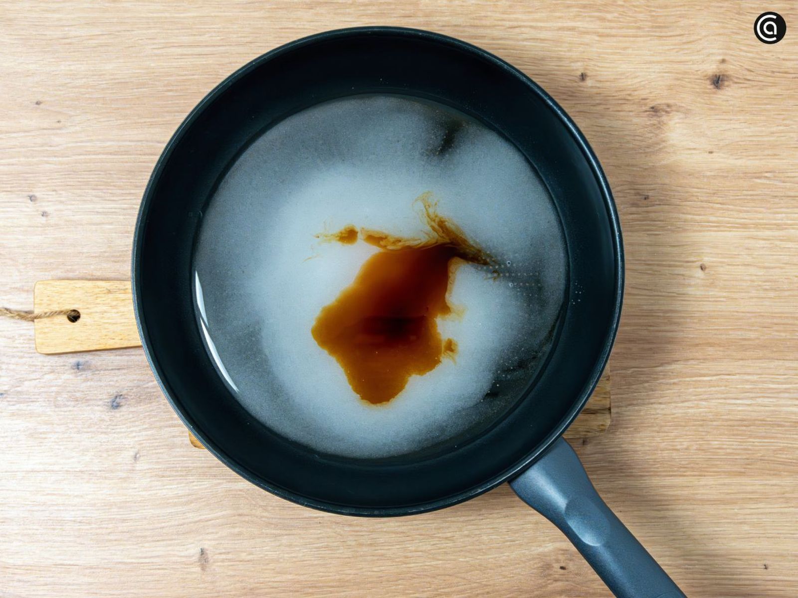 Mezcla el azúcar con el agua y la vainilla en una sartén amplia