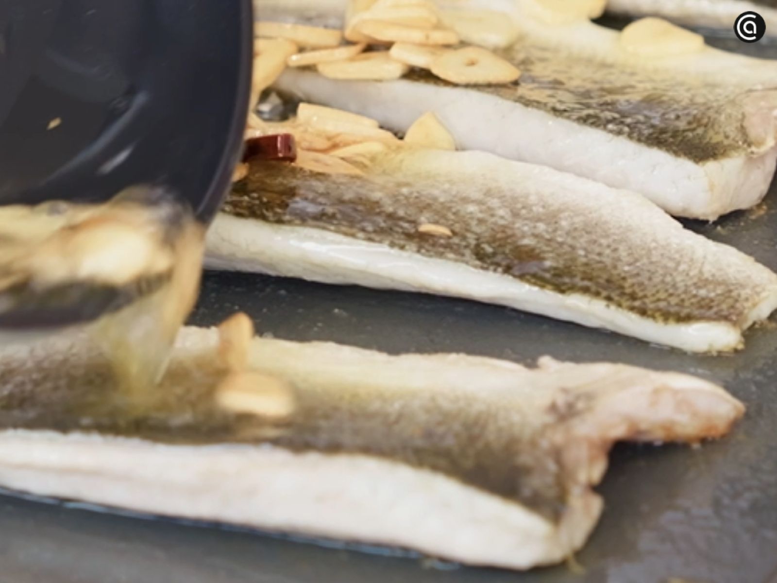 Rehoga los ajos laminados con la cayena en aceite hasta que se doren y vierte el sofrito sobre la lubina.