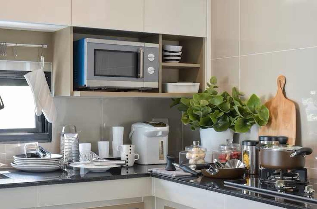 Microondas suspendido debajo de los muebles altos de la cocina.