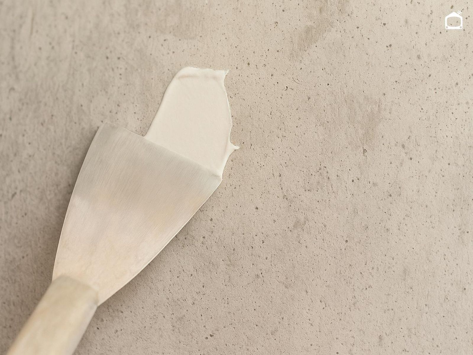 Aplicar masilla en la pared con una espátula. Aplicar masilla en la pared con una espátula.