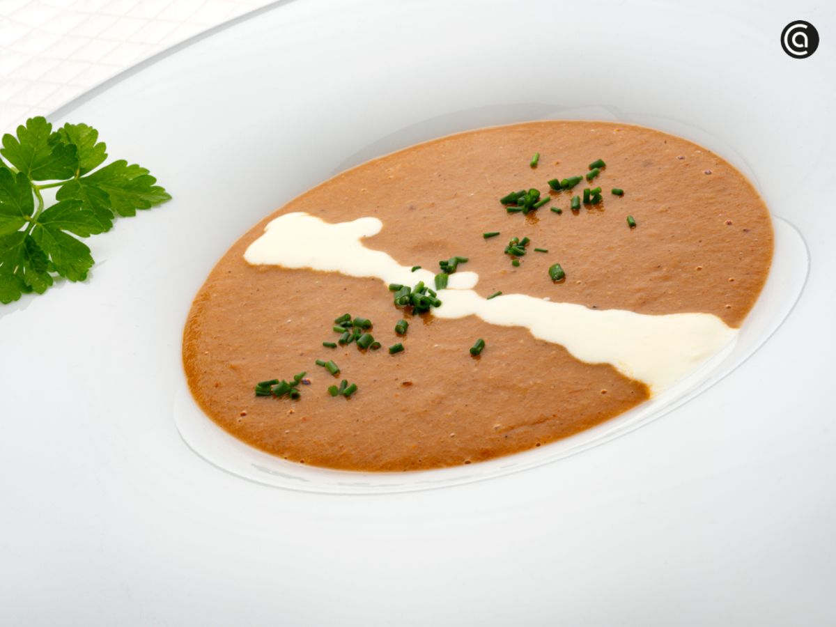 Sopa de mejillones cremosa, servida con un hilo de nata y cebollino fresco.
