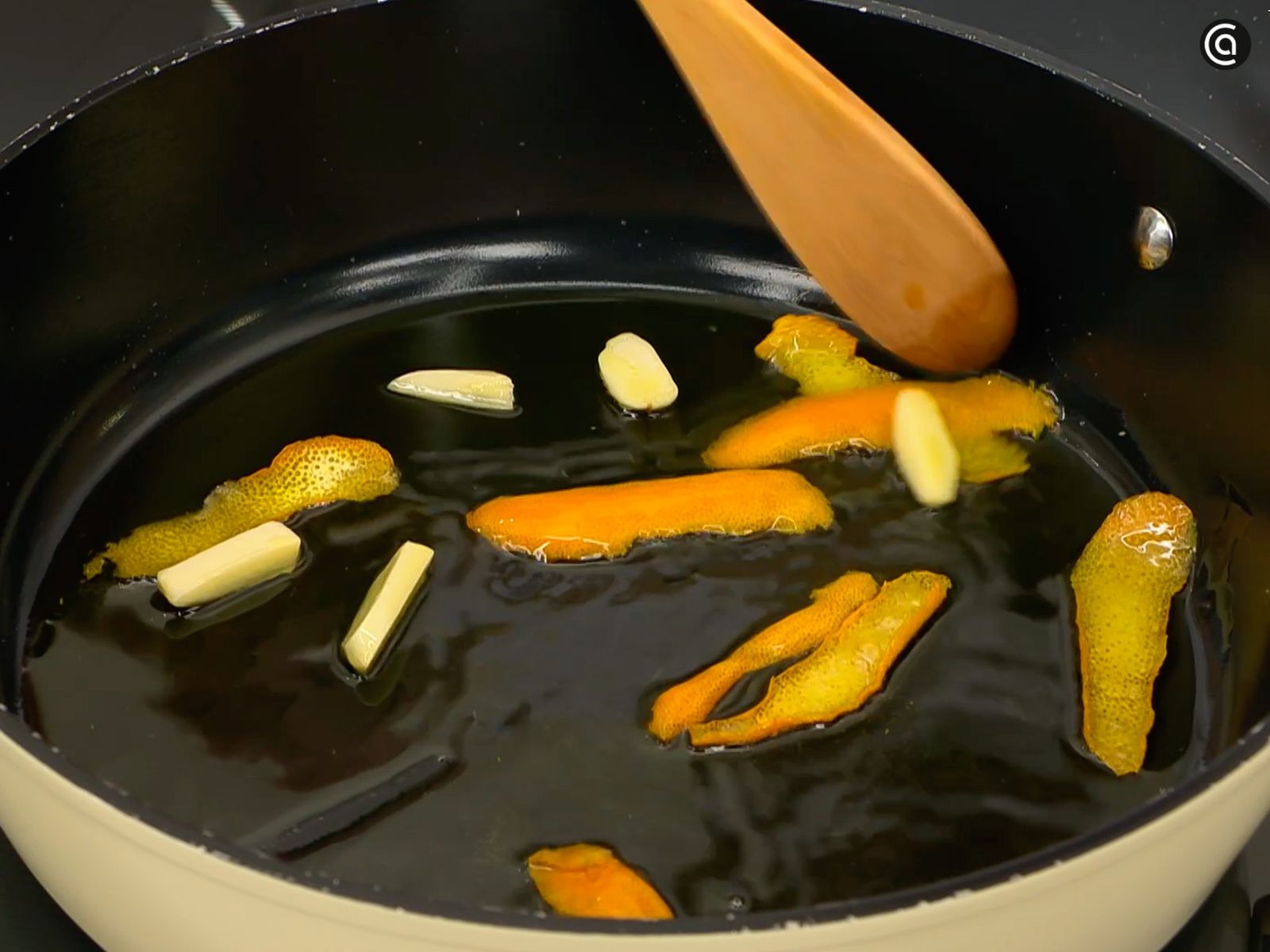 En una cazuela, sofríe los ajos en aceite con la piel de una naranja