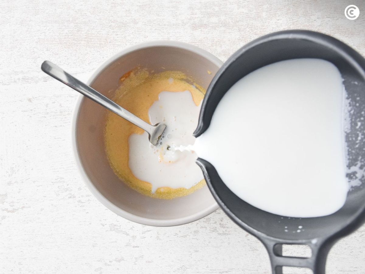 Añadir la leche caliente a la mezcla de yemas para la base del helado de leche