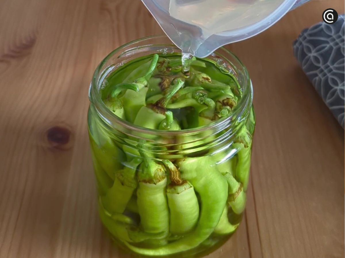 La mezcla de vinagre y agua se vierte en el tarro hasta cubrir por completo las guindillas.