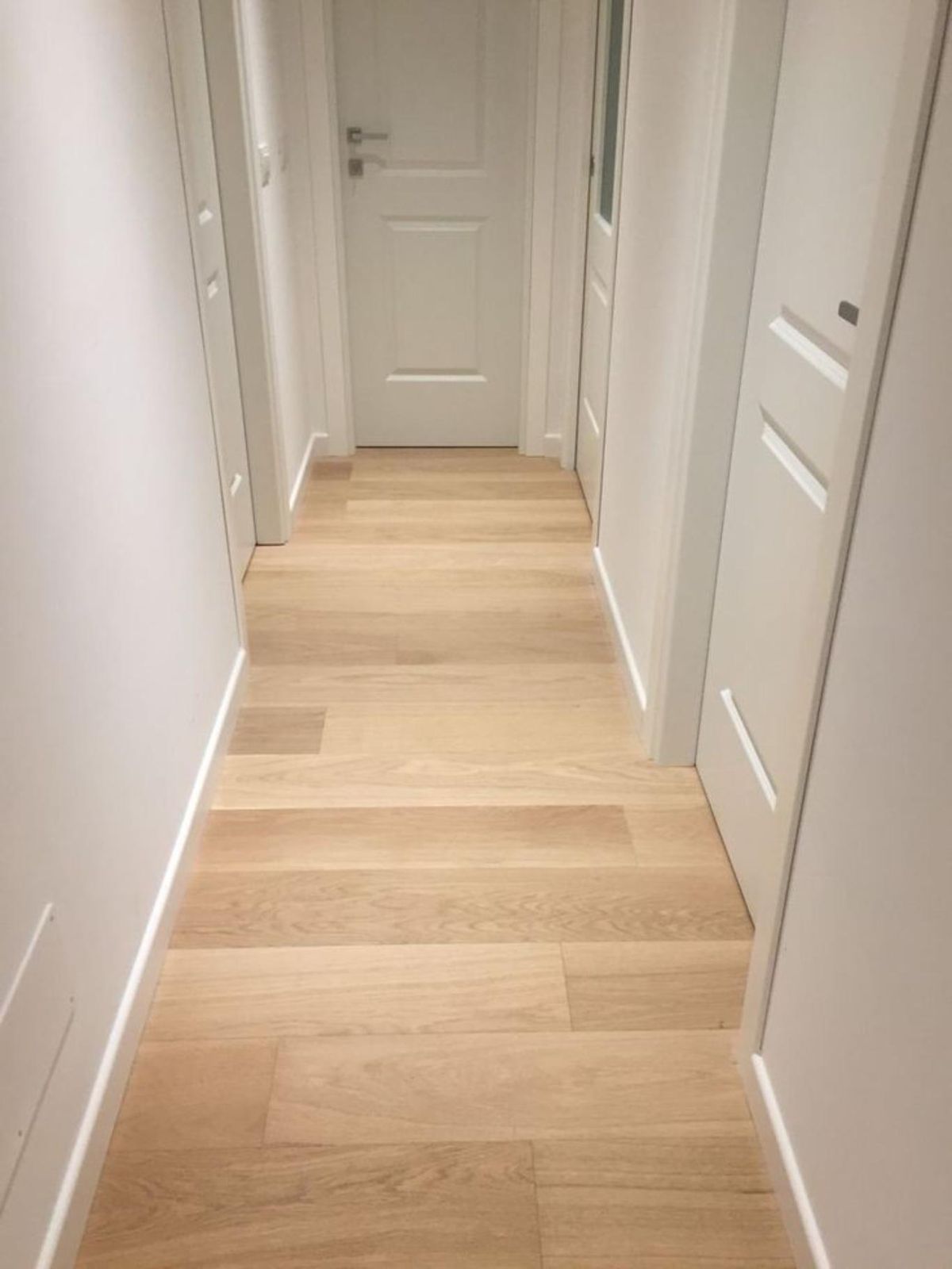 Casa con puertas blancas y suelo en roble claro.