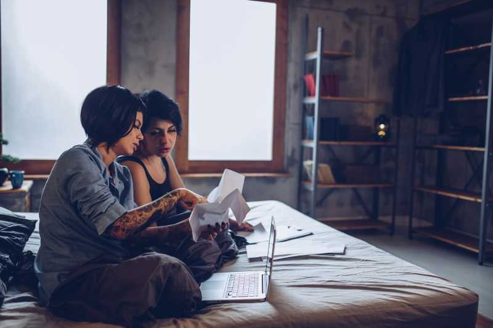 Dos mujeres mirando papeles en la cama. Dos mujeres mirando papeles en la cama.
