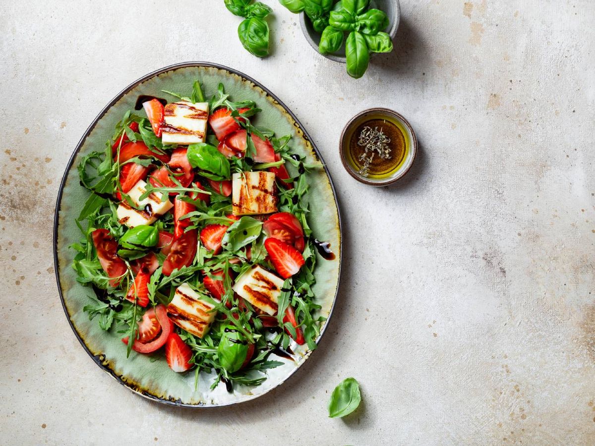 Las fresas aportan un toque dulce y ácido perfecto en esta ensalada con rúcula, tomate y queso.