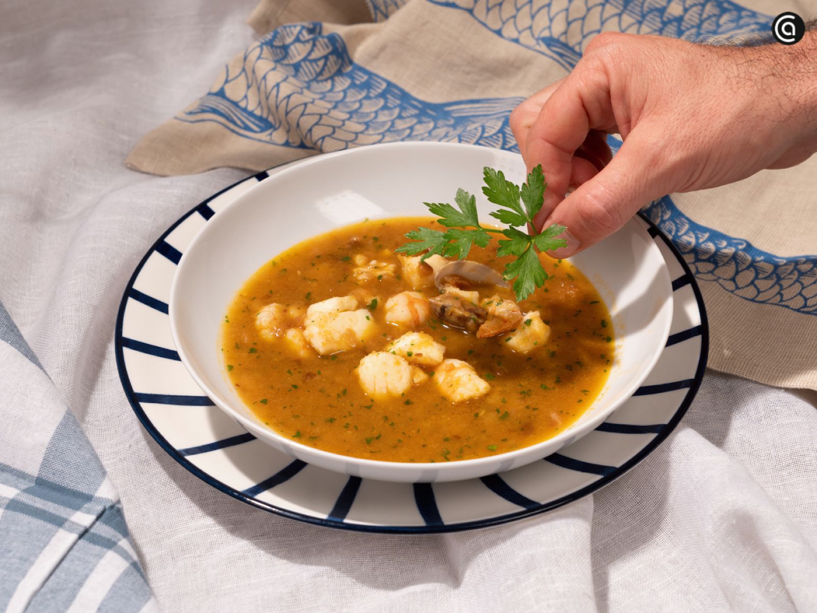 La sopa de pescado lista para servir, decorada con perejil fresco.