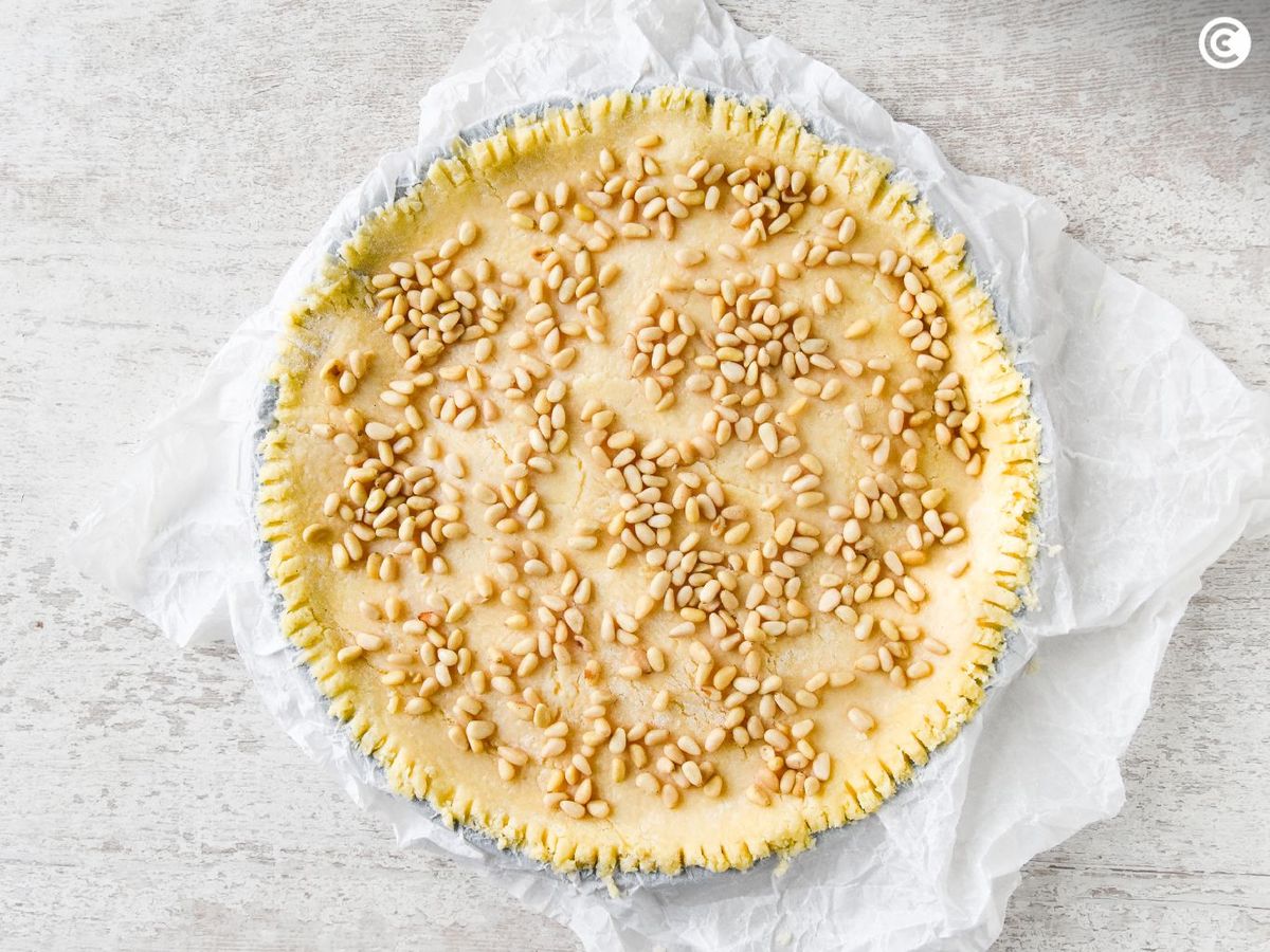 Repartir los piñones sobre la torta della nonna antes de hornearla
