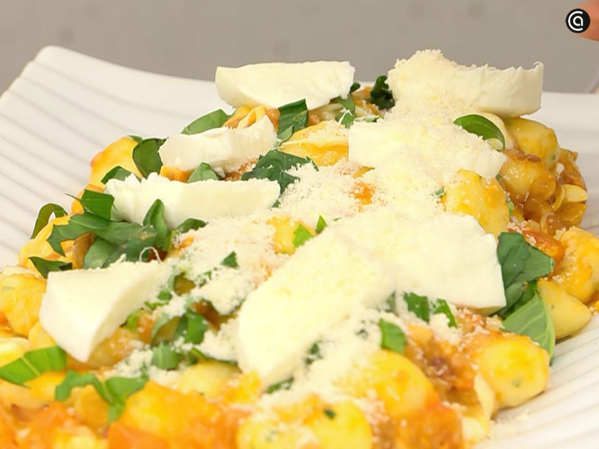 Los gnocchi se cubren con mozzarella, parmesano y albahaca antes del gratinado final.