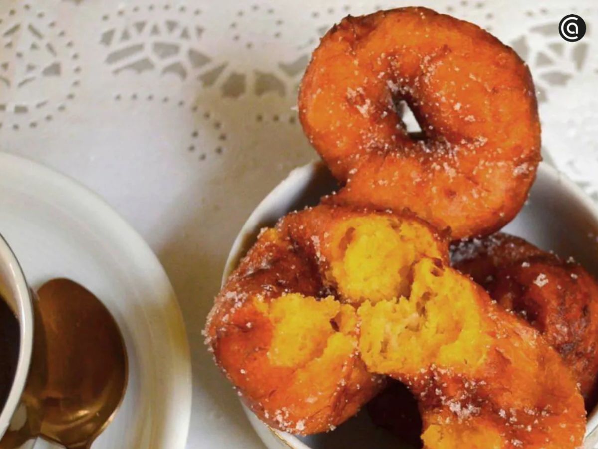 Buñuelos de calabaza, protagonistas de las Fallas de Valencia, servidos con azúcar y acompañados de chocolate caliente.