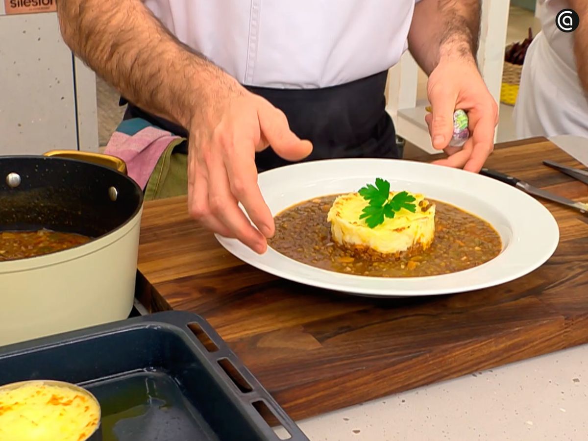 Sirve el guiso de lentejas con el pastel de patata en el centro del plato