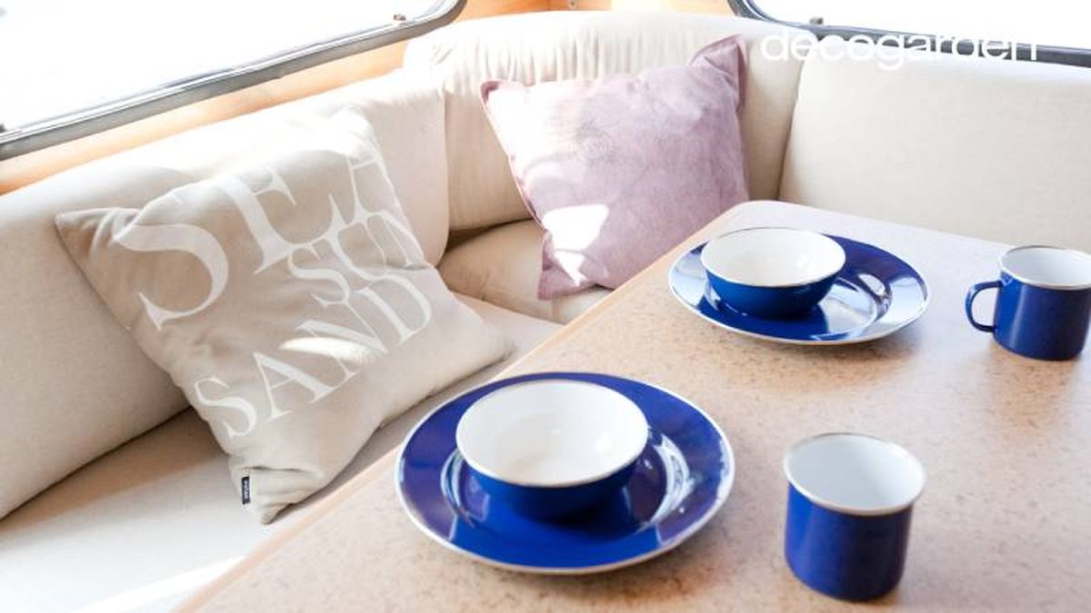 Mesa y sofá con cojines de la caravana.