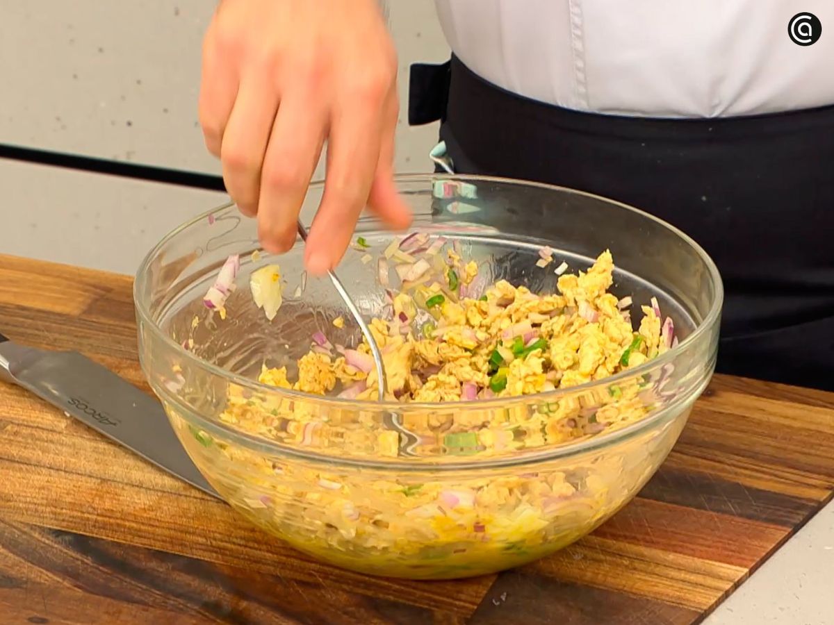 Bate los huevos y añade la cebolla, la cebolleta cortada y el pollo cocido; mezcla bien