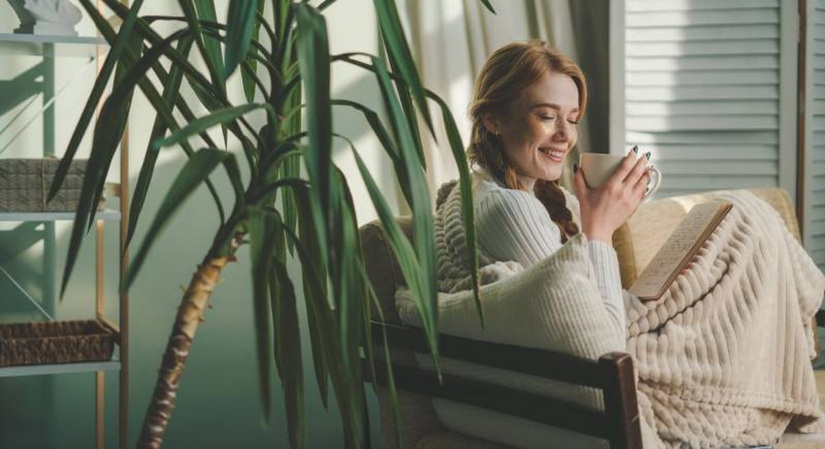 Mujer relajada en un salón decorado en verde hoja.