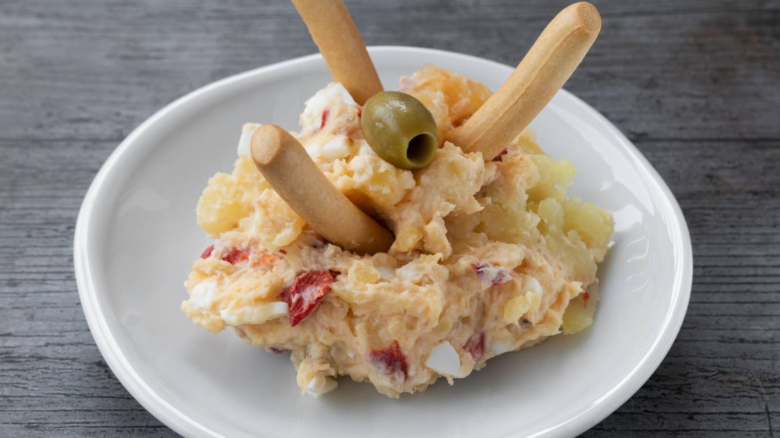 Versión clásica de ensaladilla rusa, servida con picos y aceituna. Versión clásica de ensaladilla rusa, servida con picos y aceituna.