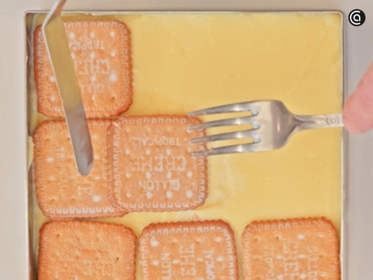 Se colocan más galletas remojadas para seguir montando la tarta por capas.