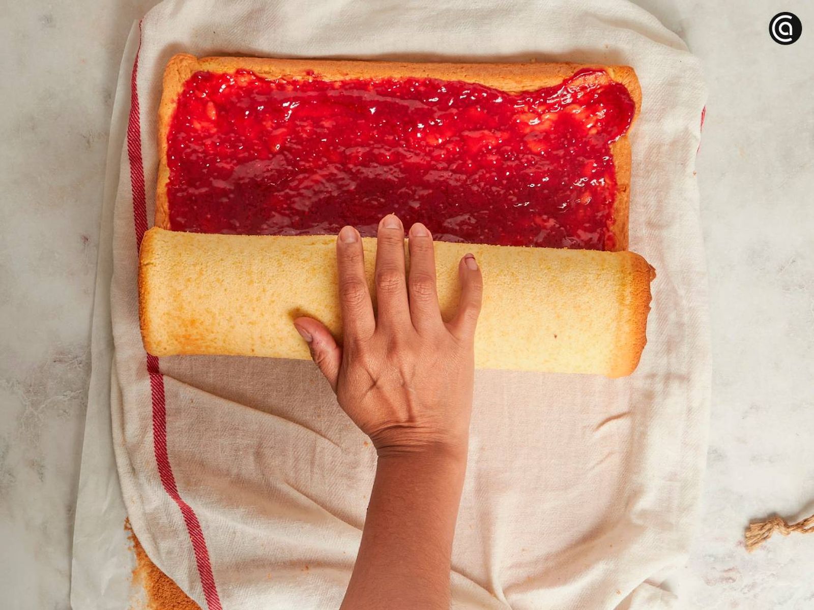 Extiende una capa de mermelada de frambuesa y enrolla