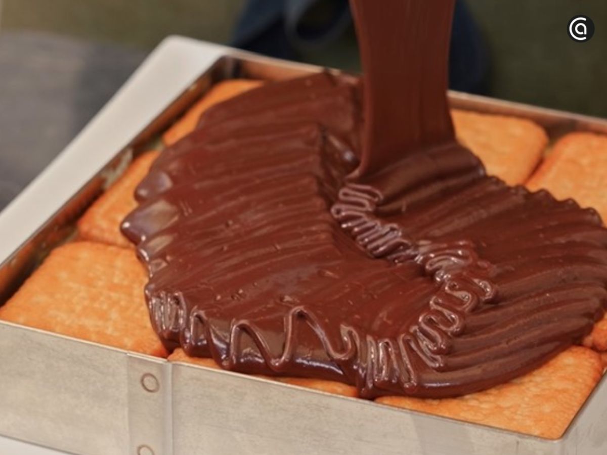 La cobertura de chocolate templada se vierte sobre la tarta y se extiende con cuidado.