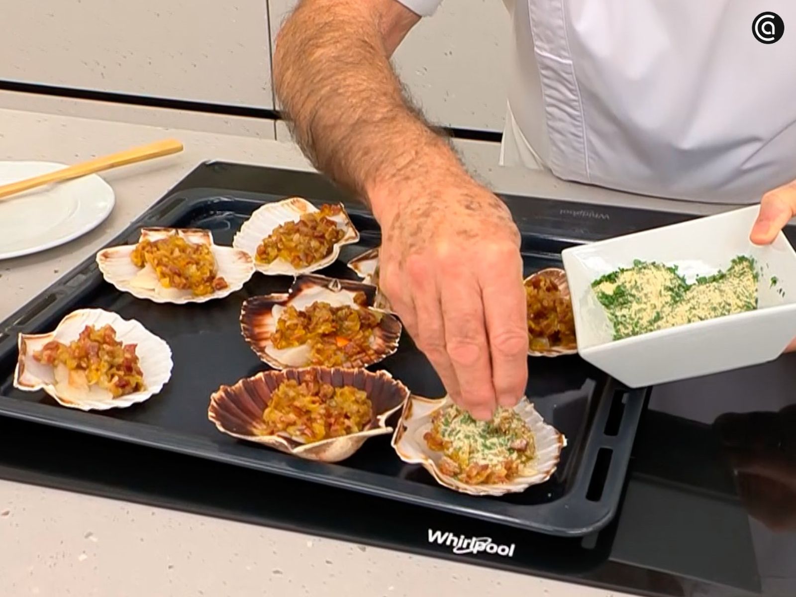 Reparte la mezcla de cebolleta y jamón sobre las vieiras, añade pan rallado por encima y gratina