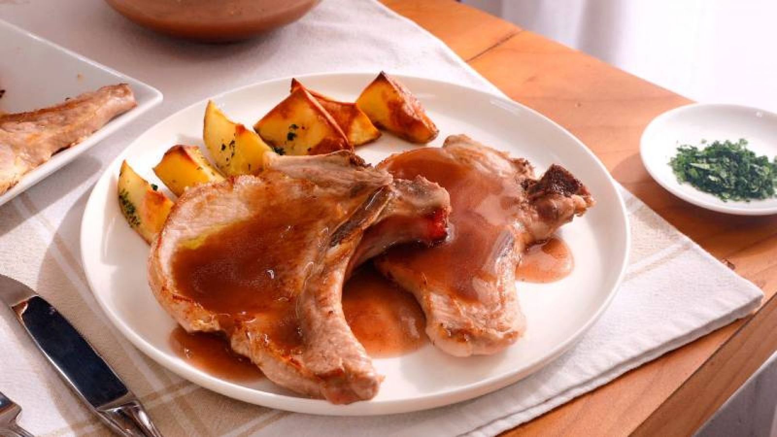 Las chuletas de cerdo se bañan en una sabrosa salsa de Oporto, creando una combinación perfecta con las patatas asadas Las chuletas de cerdo se bañan en una sabrosa salsa de Oporto, creando una combinación perfecta con las patatas asadas